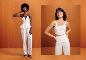 Imagem com fundo marrom com duas mulheres uma esta usando uma blusa de alça com babado na barra branca e uma calça branca e a outra esta usando um cropped branco com uma calça branca.