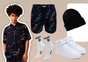 Imagem com fundo bege claro com um homem usando uma camisa preta estampada e ao lado um bermuda preta estampada, um meia branca estampada, tenis branco e uma touca preta.